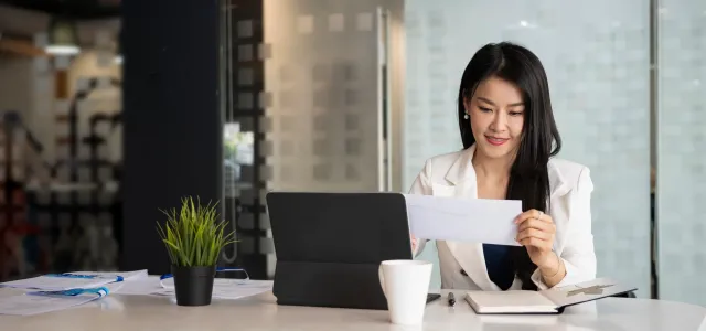 Woman sitting at desk holding mail