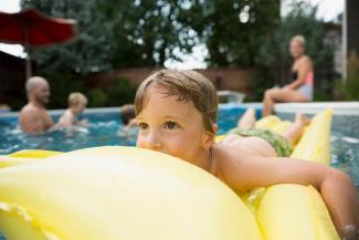 child on flotation device in a pool