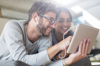 young couple smiling and looking at a tablet