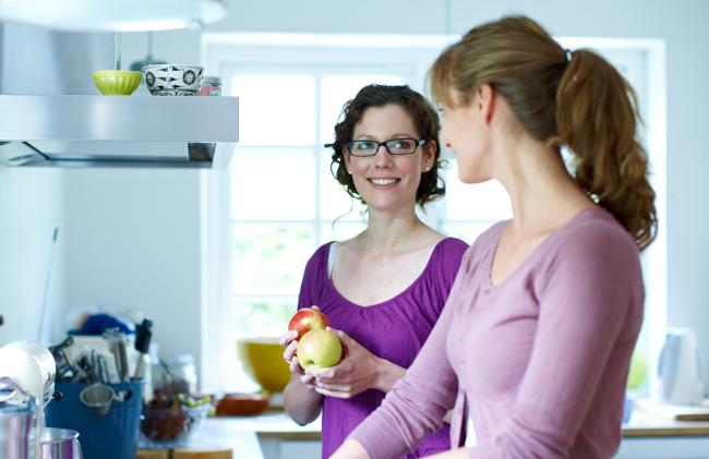 two women talking to each other in the kitchen