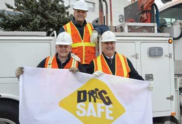 three workers holding up a dig safe flag