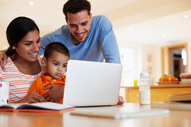 family smiling while looking at a computer