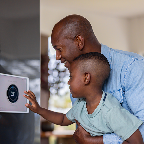 Father and son adjusting thermostat