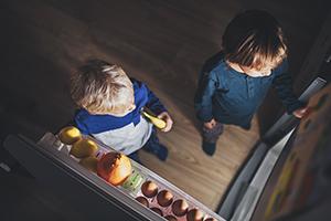 arial view of two young children standing in front of an open refrigerator