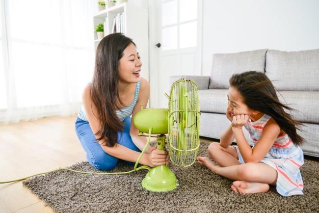 woman holding a fan in front of a young girl